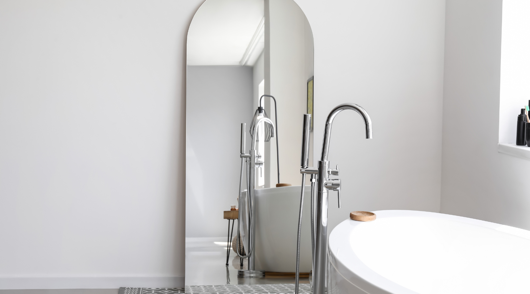 Free-standing leaner arch mirror in a bathroom next to a free-standing bath.