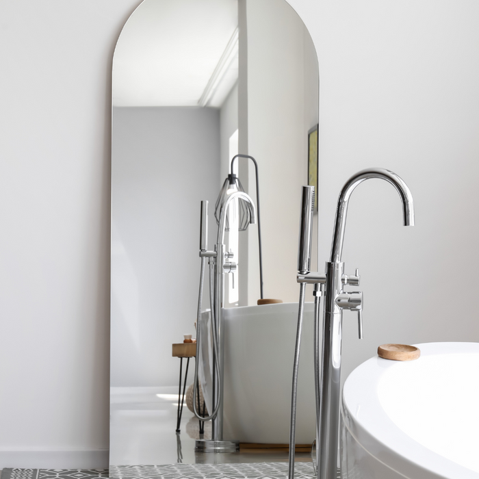 Free-standing leaner arch mirror in a bathroom next to a free-standing bath.