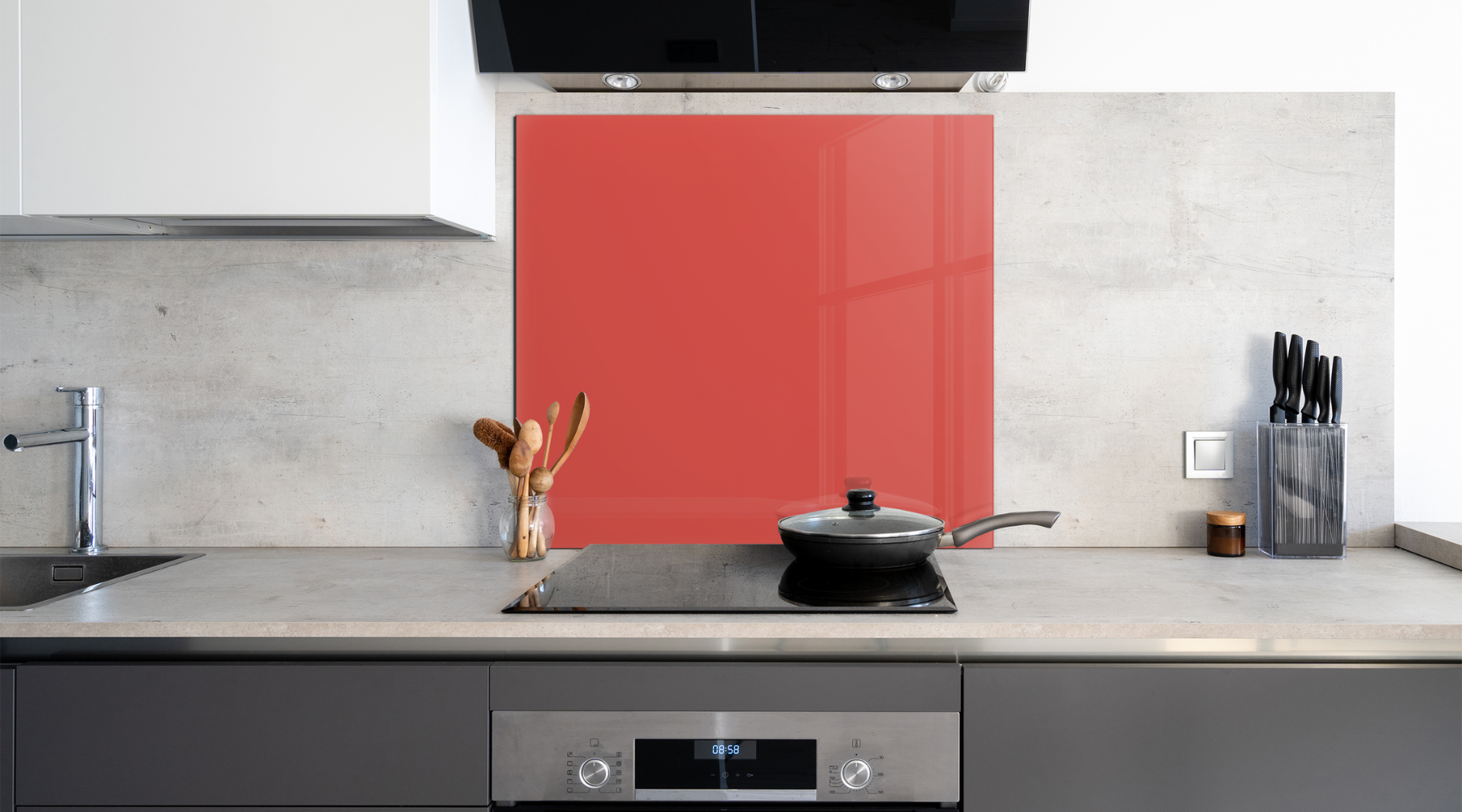 A square red glass painted backsplash behind modern electric hob in a clean kitchen space.