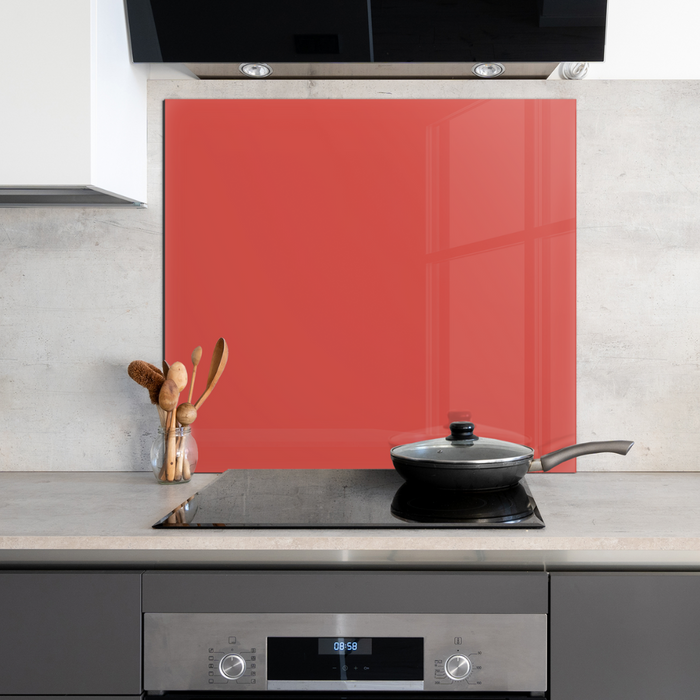 A square red glass painted backsplash behind modern electric hob in a clean kitchen space.